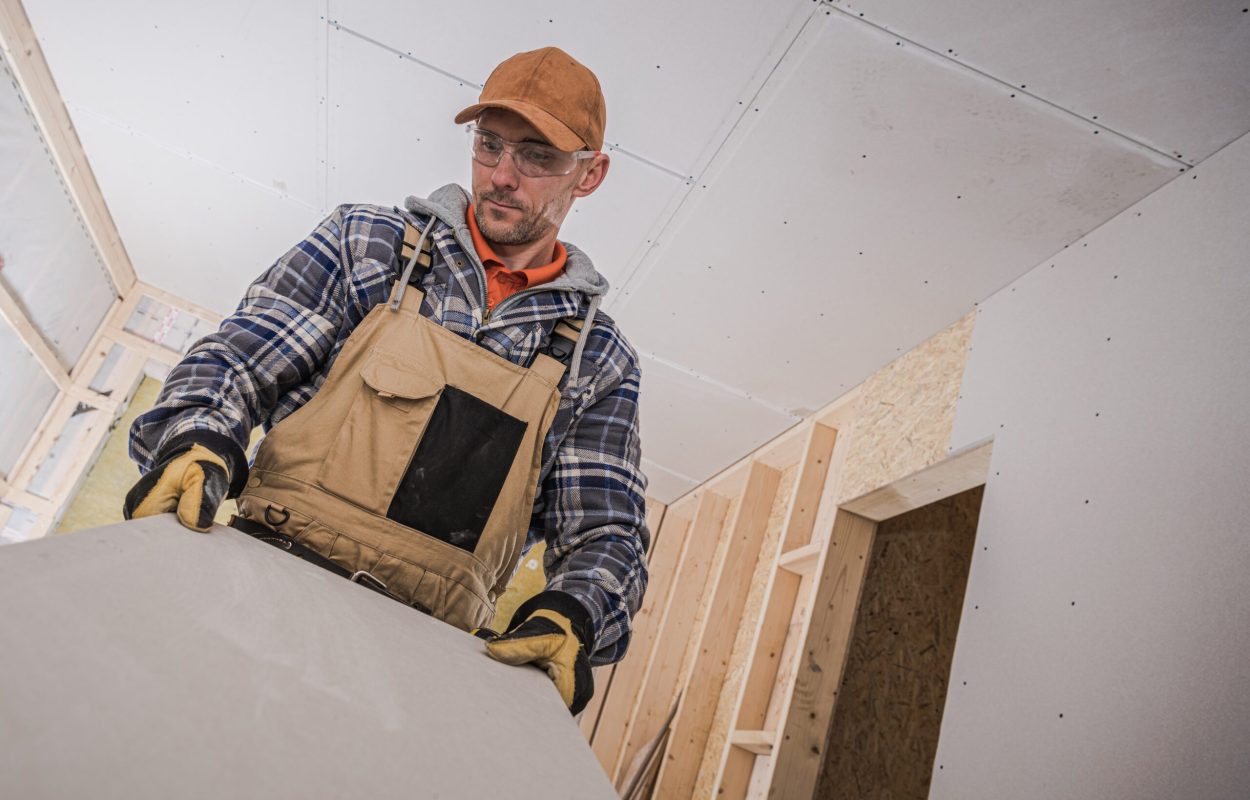 Sheet Rock Drywall Material Installation by Caucasian Construction Worker. House Interior Finishing.