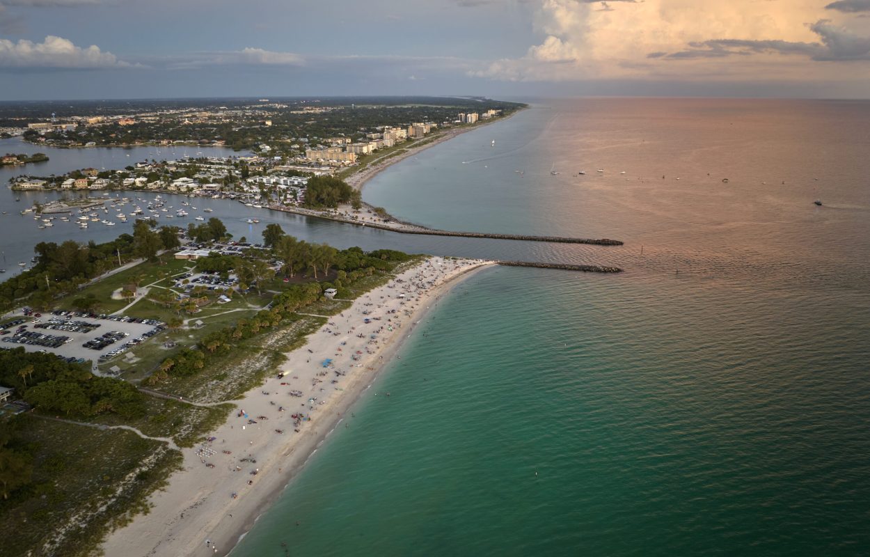 High angle view of crowded Nokomis beach in Sarasota County, USA. Many people enjoing vacations time swimming in ocean water and relaxing on warm Florida sun at sundown.