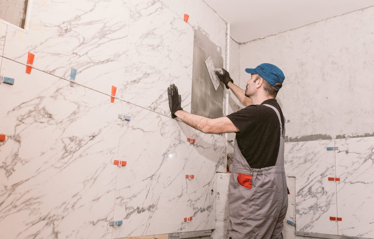 Handyman instaling ceramic tiles on the bathroom wall